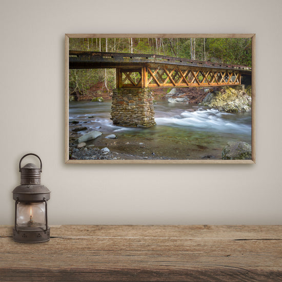 This piece of masculine wall art captures the steadfastness of an industrial bridge against the calming backdrop of a flowing river.