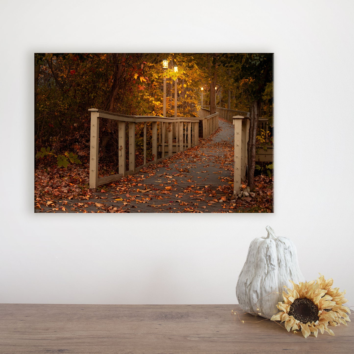 This art piece displays the Woodlawn Beach boardwalk bathed in the soft glow of dawn and surrounded by fall leaves, serving as both versatile wall art and seasonal living room decor for autumn.