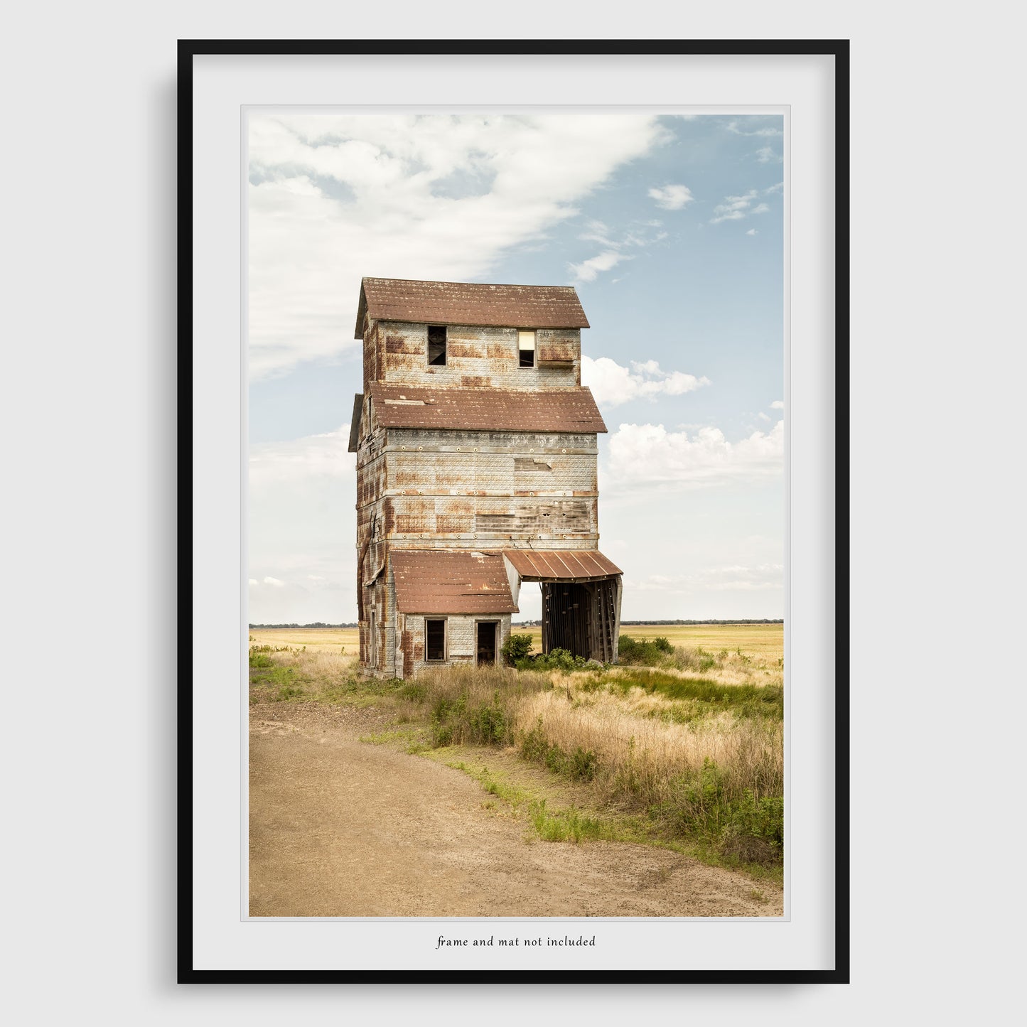 An engaging print of the Ardell grain elevator under a soft, cloud-dappled blue sky, set against the serene landscape of Kansas.